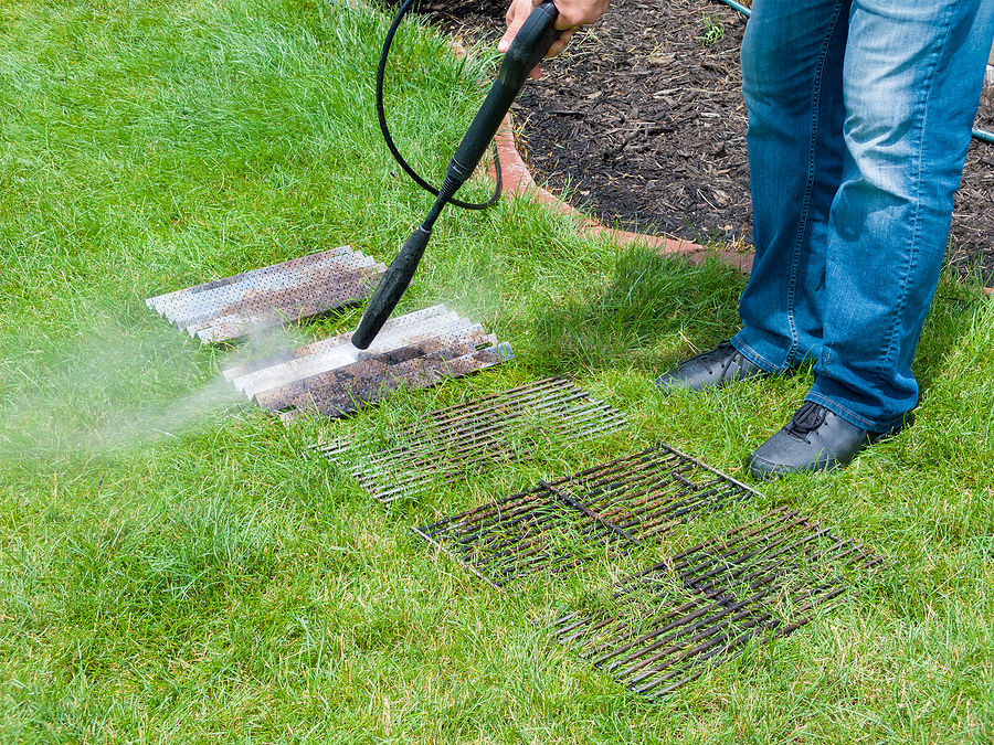 Outdoor barbecue and grill being cleaned with a pressure washer