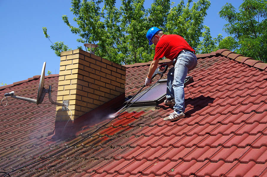 Chimney stack being cleaned of moss and soot staining